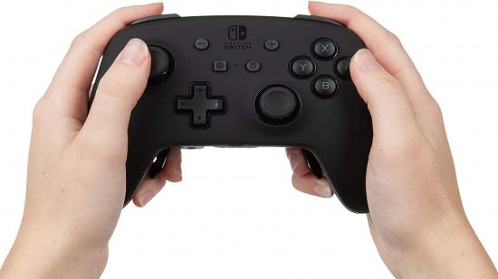 Two hands holding a black Nintendo Switch gaming controller