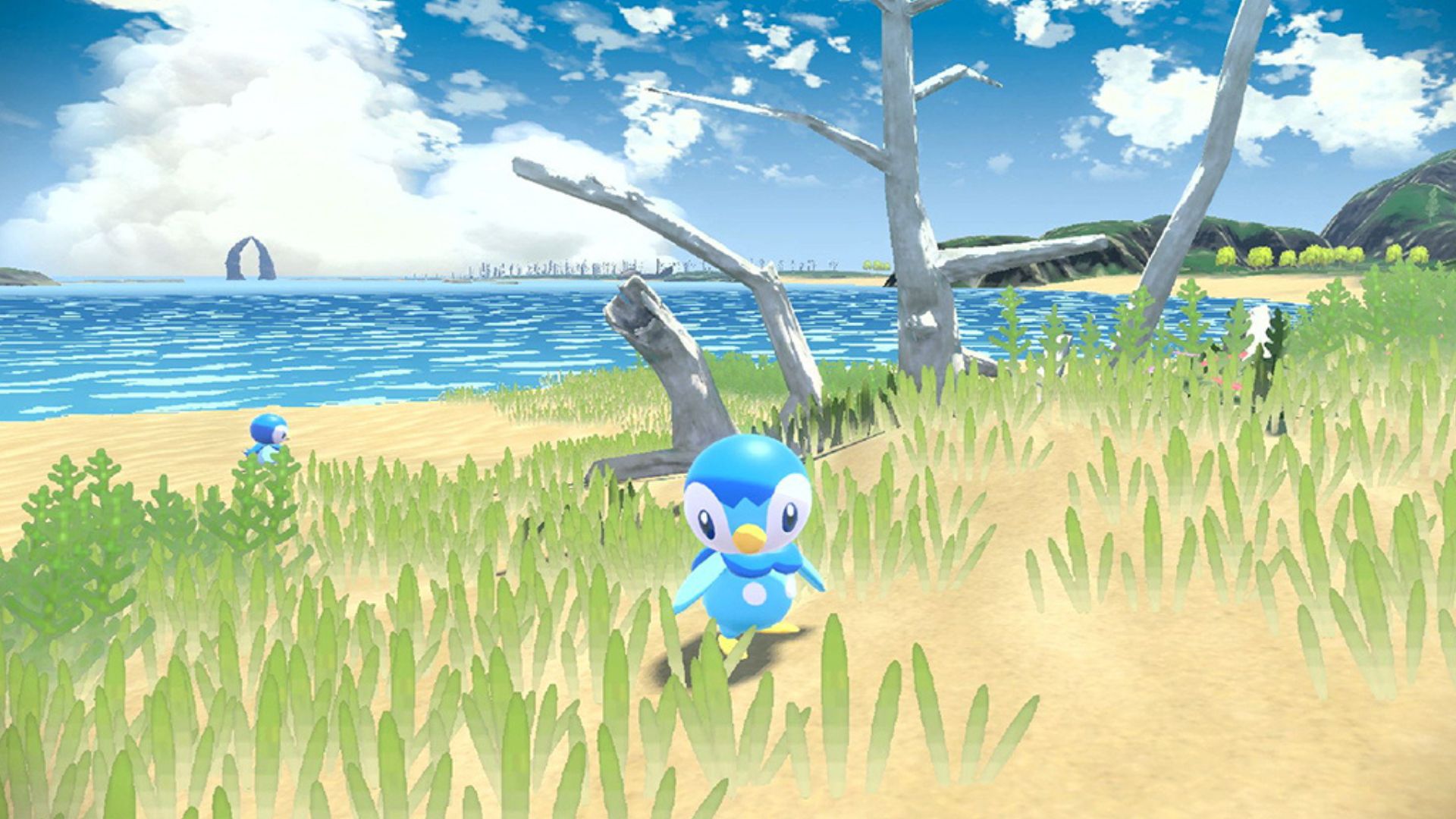 Best monster games: Pokémon Legends: Arceus. Image shows Piplup, a small bird, standing in some grass near the ocean. 