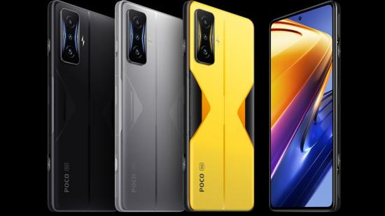 Four Poco F4 GT phones. Three have their back to us, showing off the camera and the three colours: yellow, silver, and black. The fourth phone has its screen to us, showing a futuristic black and orange background.