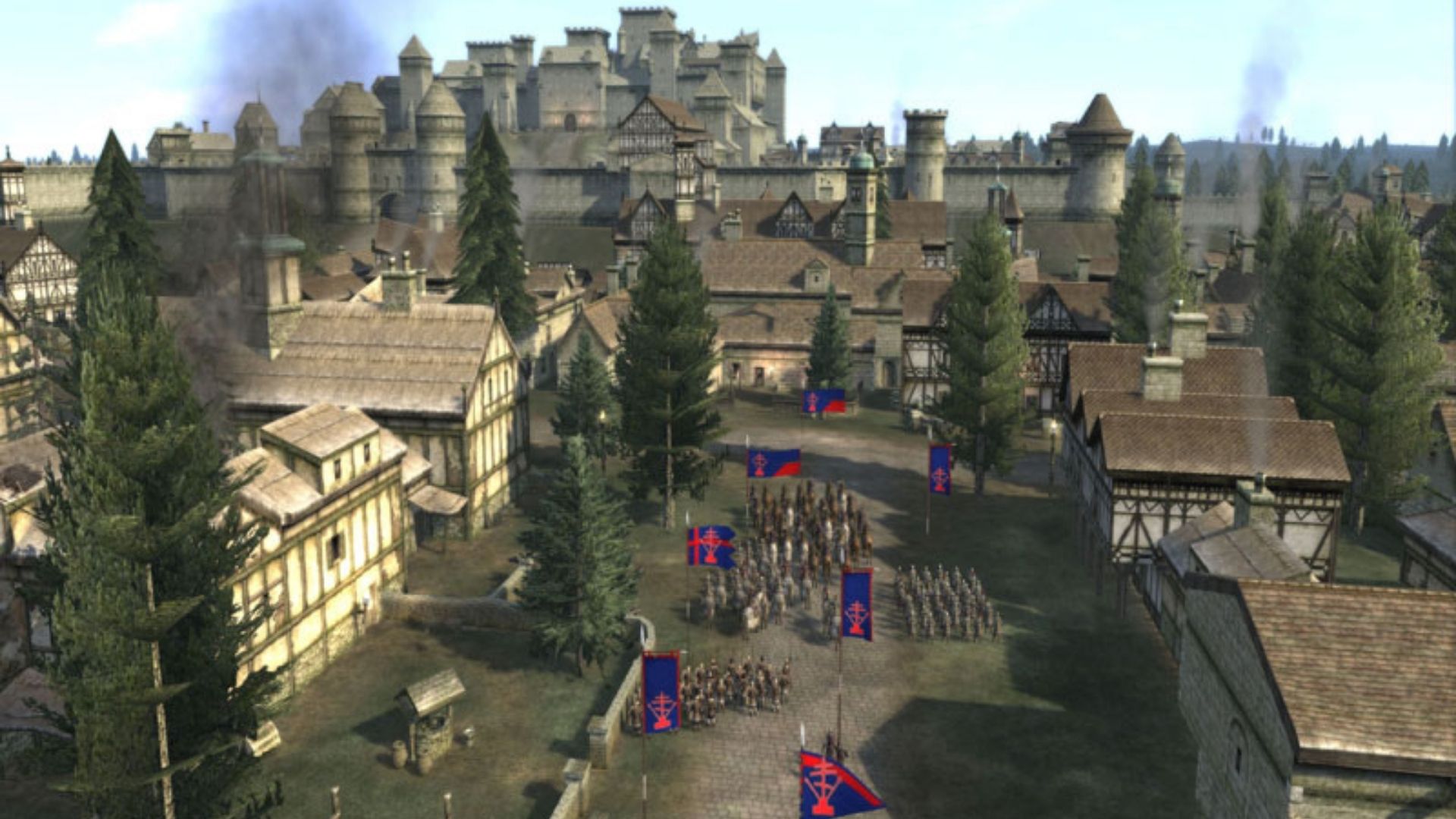 A screenshot from Medieval II Total War, showing hundreds of soldiers in a town from a bird's eye view, with a castle in the background.