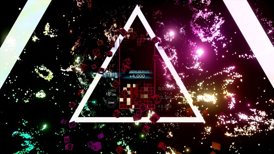 One of the many Tetris games, Tetris Effect Connected, mid-game, showing a dark red Tetris game with a triangle of light surrounding the grid. Sparks of yellow, red, and purple litter the border.