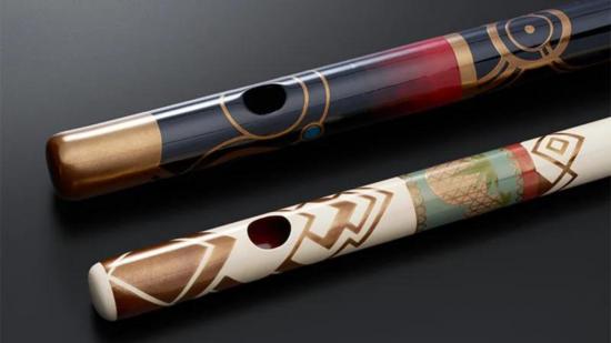 The two Xenoblade Chronicles 3 flutes, custom built for the game. One is black, with red and gold detailing. One is white, with green, red and gold detailing.