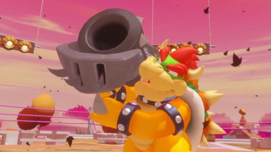 Bowser, a large dinosaur crossed over with a turtle, holding up a cannon on his right shoulder. The sky is pink, below it in the distance are buildings that look like they're made from sweets. Everything is eye-popping.