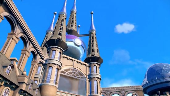 A building with multiple spires coming out of the top, in the middle of which is a large Poke ball. It looks a bit like the Sagrada Familia. The sky is blue, with barely a cloud in sight, in a screenshot from Pokemon Scarlet and Violet.