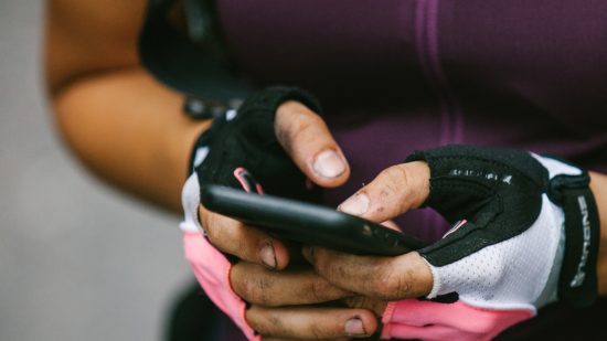 Fitbit apps - someone in bike gloves typing on their phone