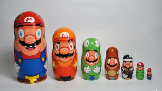 Various Mario matryoshka dolls lined up. From right to left: a large blue dungaree-wearing Mario, a smaller one with an orange hat, a smaller, yoshi-esque Mario, an even smaller brown Mario, and a tiny black Mario.