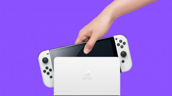 One of the best portable gaming consoles, the Nintendo Switch OLED, in its dock with a hand reaching to pull it out. It has white controllers and a white dock.