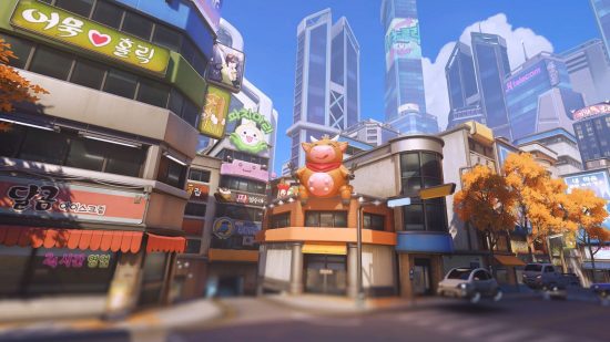An Overwatch 2 map showing a scene of tall skyscrapers, small corner shops, and a general bustling city.