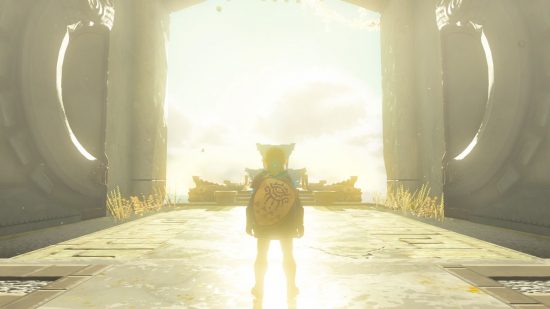 A screenshot from The Legend of Zelda: Tears of the Kingdom showing Link stood in from of a large open archway with bright light shining through.