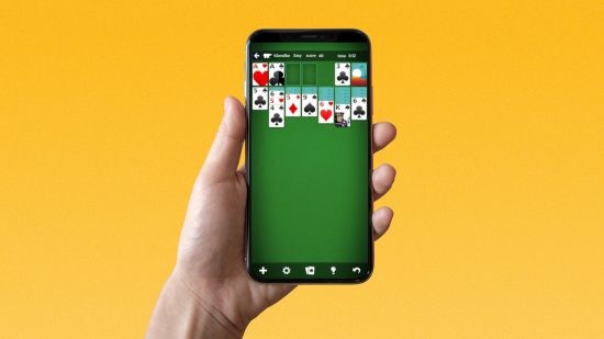 Play Solitaire - a hand holding a phone with Solitaire on the screen