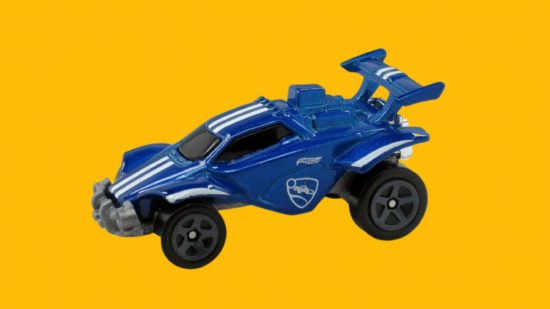 Rocket LEague Hot Wheels- a blue car with larger rear wheels and large spoiler with white stripes down it's middle, kinda like a dune buggy, on a mango-yellow background.