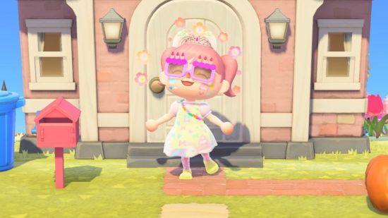 Games like The Sims: A screenshot from Animal Crossing New Horizons showing a character with pink pigtails, birthday cake glasses, and a yellow and pink dress and outfit emoting with flowers in front of a pink house with a dark pink mailbox and a pumpkin off to the right.