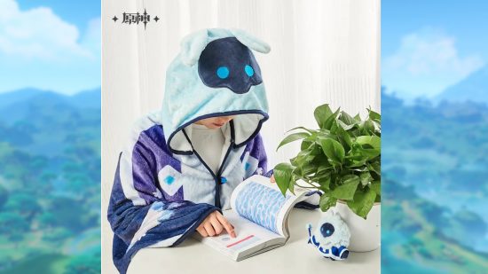 Genshin Impact merch: A picture of a person wearing the cryo Abyss Mage hooded blanket and reading a book at a table.