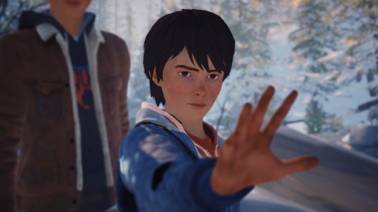 Life is Strange 2 review: Daniel holding his hand out towards the camera with a concentrating look on his face. He wears a blue jacket over a red tshirt and his brown hair is slightly too long in the front. His brother Sean stands in the background in a brown jacket over his dark blue hoodie.