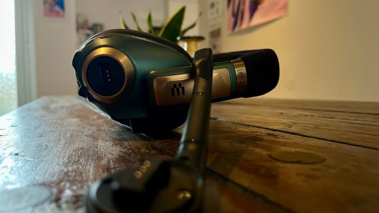 Epos H3Pro review - a pair of over-ear headphones with a microphone detached, lay on its side next to the lying down headphones on a wooden table.