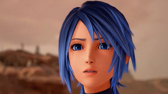 Kingdom Hearts Aqua, a woman with blue hair in a sort of bob, a black sleeveless armour that looks like leather, with straps in a cross across the chest, spiky boots and a key as a blade. Here is a shot of her face close up. She looks quietly concerned against a desert landscape.
