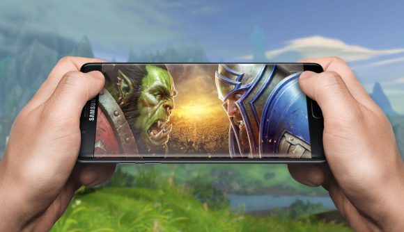 A hand holding a phone with WoW's battle for Azeroth art on it