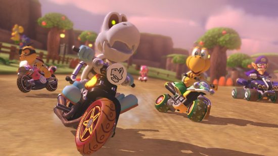Mario Kart 8 Deluxe screenshot, a good bike game, showing multiple characters on bikes on a dirt track banked by grass and fences. In the middle is a skeleton creature, on the right the skin version of him.