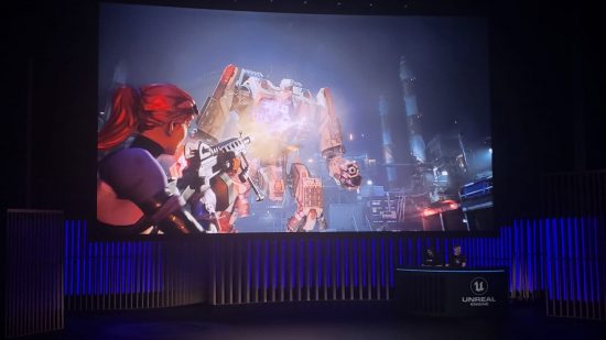 A photo of the Fortnite Creative UEFN demo at State of Unreal 2023. A darkened stage below, a massive screen showing a woman shooting a giant robot above.