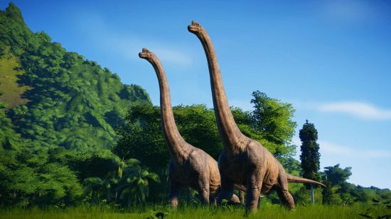 Jurassic World games - two long necked dinosaurs walking across grass past dense jungle rising up a large hill. I think they're called diplodocus.