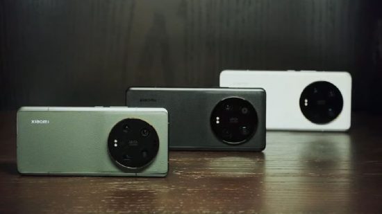 Xiaomi 13 Ultra release date -- Three phones on their side back showing, on a wooden shelf. One is green, on the left, black in the middle, white on the right. The back has a large circular camera on the right hand side.