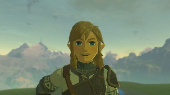 Zelda Tears of the Kingdom shield surf - Link, a blonde boy in a white and brown tunic standing smiling at the camera. Behind him is a mountain range and a low orange sunset.