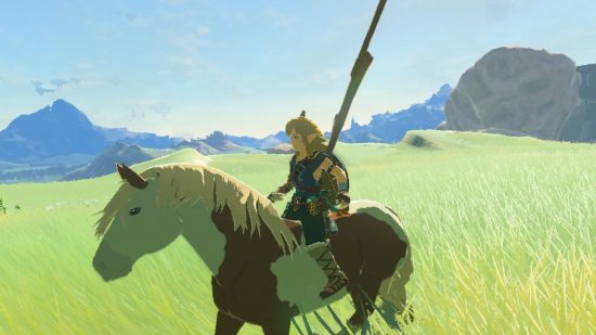 Stajnia Zelda Tears of the Kingdom - Link, blondyn na koniu obok innych koni jadących na grzbiecie z górą wypluwającą czerwone światło daleko w oddali.
