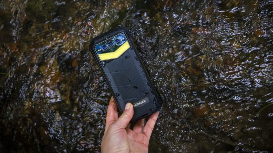 The Doogee S100 Pro phone held in a stream to test its waterproof rating