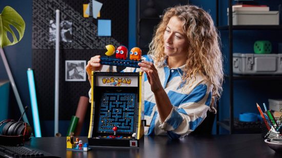 Lego Pac-Pam: zdjęcie produktu przedstawia kobietę o długich blond kręconych włosach bawiącą się automatem do gier Lego Pac-Man