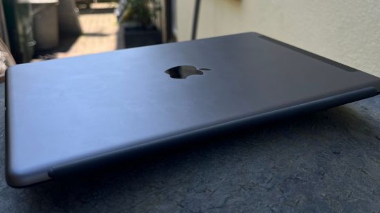 iPad 9 Gen review shot, showing the iPad in black lying on its front, back up with the Apple logo in the middle.