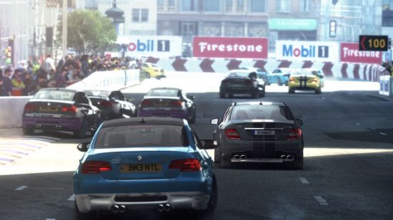 Offline game Grid Autosport screenshot showing multiple cars driving down a tarmac track with shadows cast over it by nearby buildings.