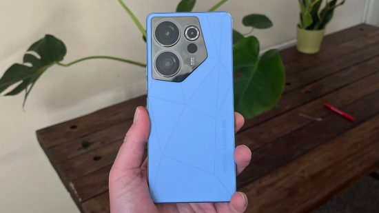 Tecno Camon 20 Premier review - a phone held in a hand with the back to the camera. The back is blue with large camera lenses in the top left corner.