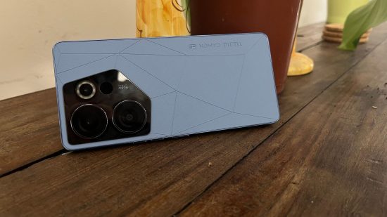 Tecno Camon 20 Premier review - the phone lying on its side leans against a yellow candlestick. The back has a blue leather design and big cameras in the corner.