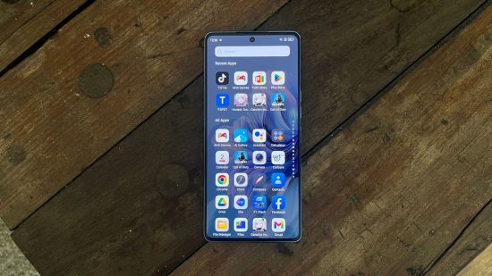 Tecno Camon 20 premier review - the phone on its back on a wooden table. The screen is on showing a load of apps in a menu..