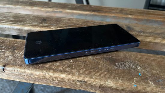 Tecno Camon 20 Premier review - a phone flat on its side on some wood, with slightly blue metal sides and black screen.