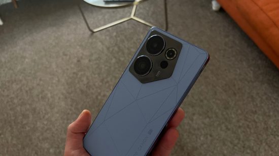 Tecno Camon 20 Premier review - a phone held in a hand with the back to the camera. The back is blue with large camera lenses in the top left corner.