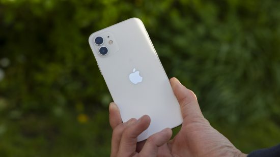 The back of a white iPhone 12 being held in a man's hands
