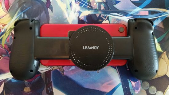 Recenzja LeadJoy M1: Tył kontrolera LeadJoy M1 przymocowany do czerwonego iPhone'a SE, ukazujący płytkę chłodzącą.  To jest na podkładce pod mysz Genshin Impact.