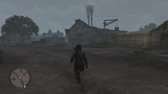 Read Dead Redemption Switch review screenshot showing a cowboy walking along a dirt track in front of a rickety building with two smokestacks coming from the top and a small crane behind.