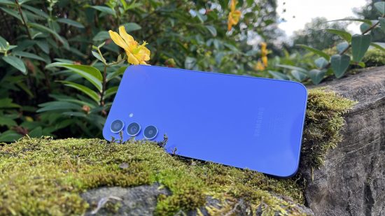 Samsung A54 review - he back of a Samsung A54 sitting on a mossy log