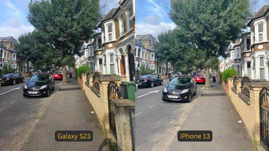 Samsung Galaxy S23 review photo comparison showing the S23 on the left and iPhone on the right, with identical pictures. They are both of a street with cars and houses and a large tree as the focal point in the centre ahead.