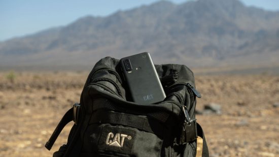 Android satellite connectivity header showing a black phone sat on top of an upright black CAT backback in front of a tall deserty landscape in front of a large hill or mountain.