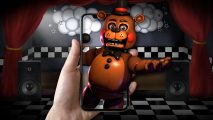 FNAF games - a person's hand holding a phone against a stage background as FNAF Freddy pops out of it