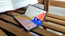 Galaxy Z Fold 4 review - a photo of the phone half-open on a wooden bench, displaying the home screen and a selection of apps