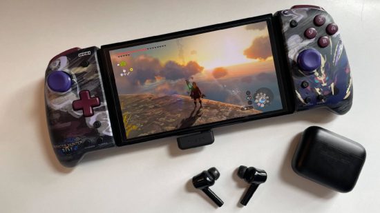 Razer Hammerhead Pro HyperSpeed review: The Razer Hammerhead Pro Hyperspeed earbuds are sat next to a Nintendo Switch OLED, with the Razer USB-C dongle inserted into the bottom the device