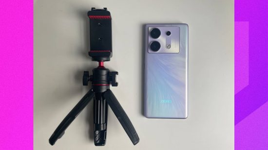 Infinix Zero 30 5G review: The Infinix Zero 30 5G is laid flat on a table, next to the tripod and selfie stick included in the box