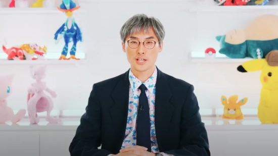 Pokemon hundreds of years: Utsunomiya presenting the most recent Pokemon Presents in a black suit and tie and blue Mew button up shirt
