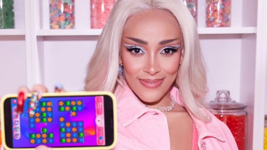Screenshot from Doja Cat Candy Crush crossover clip with Doja Cat holding a phone playing one of the games