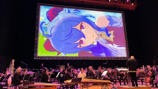 A photograph from the Genshin Concert 2024 showing Ganyu on the projector screen above the orchestra as they perform