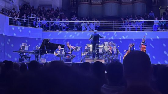 Zdjęcie zrobione podczas koncertu Stardew Valley, Stardew Valley: Festival of Seasons, z niebieską projekcją nad orkiestrą